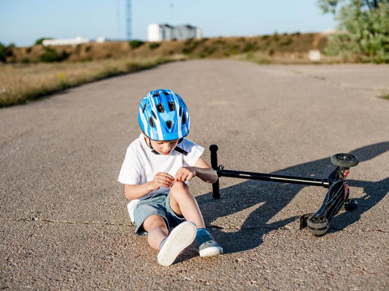 Photo of Kid with helmet holding his hurt knee